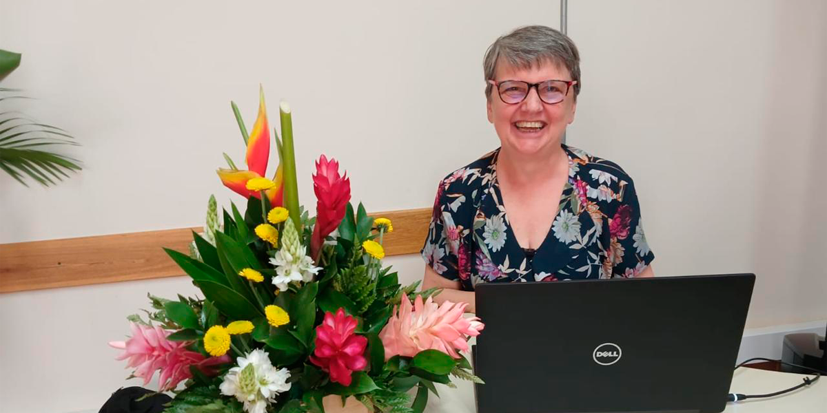 Elzbieta Bochno Hern&aacute;ndez, mujer, exparticipante de Historias en Yo Mayor, sentada frente a un computador y un ramo de flores. La imagen ilustra la nota sobre personas mayores.