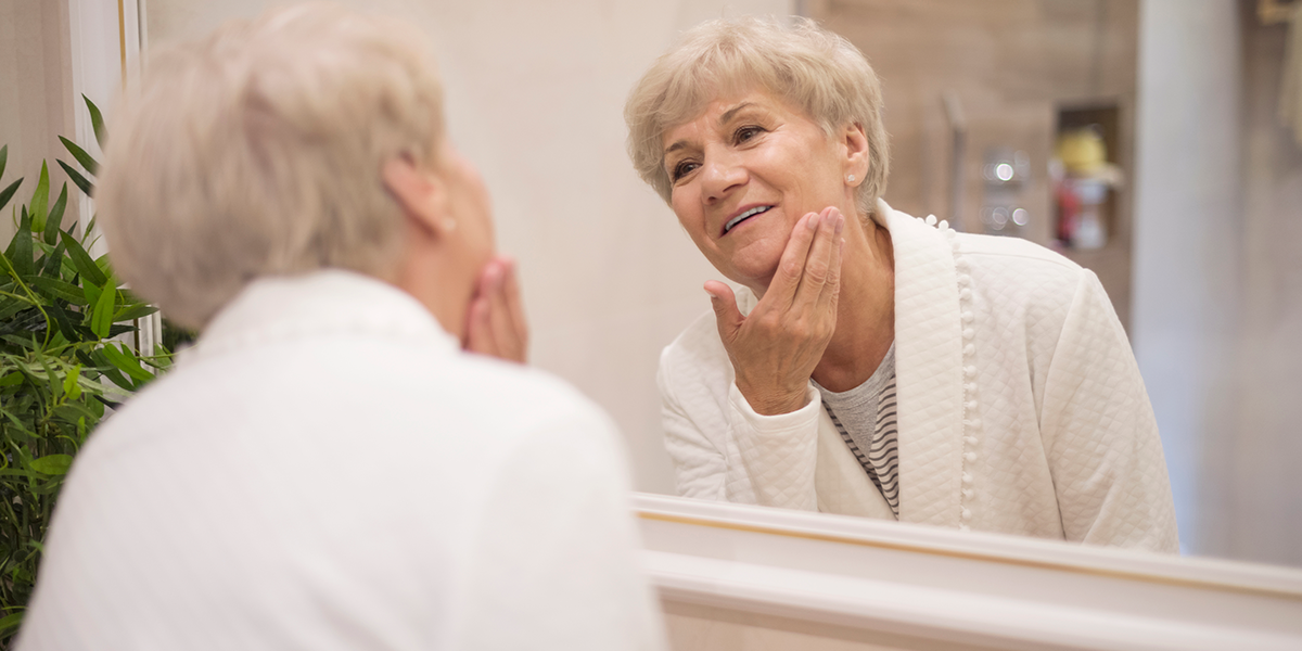 Una mujer mayor se mira al espejo. FreePik