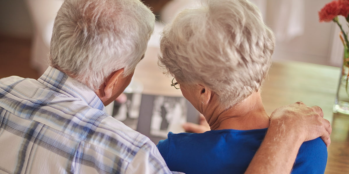 Un hombre y una mujer mayores aparecen de espaldas mientras observan fotograf&iacute;as