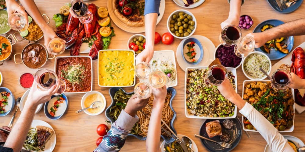 mesa con comida y amigos Mesa con diferentes tipos de comida, copas y brindis de amigos