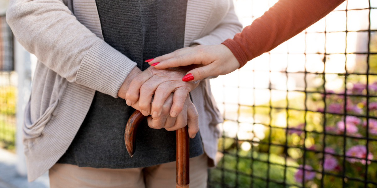 Persona mayor con bast&oacute;n es asistida o acompa&ntilde;ada