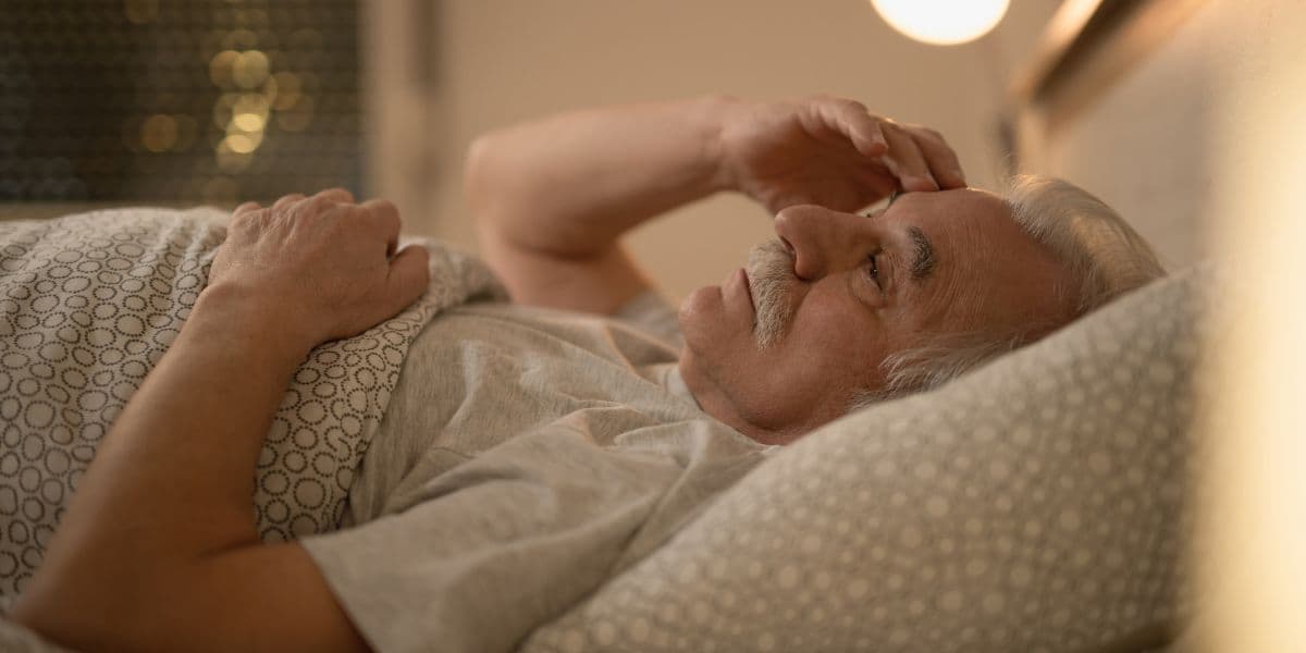 Persona mayor preocupada en cama antes de dormir. En personas mayores, un sue&ntilde;o muy fragmentado puede ser una se&ntilde;al de alerta.