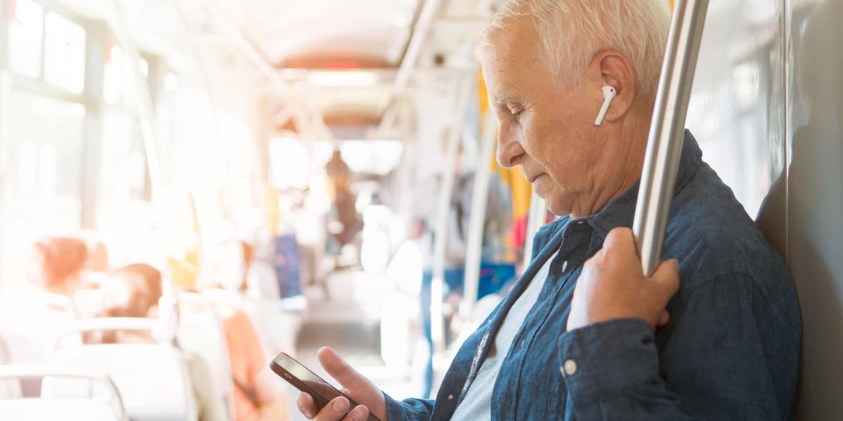 Hombre mayor viendo su celular mientras se desplaza en un sistema de transporte p&uacute;blico