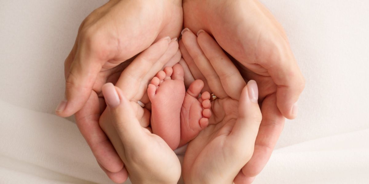 Manos adultas sujetan pies de un beb&eacute; reci&eacute;n nacido