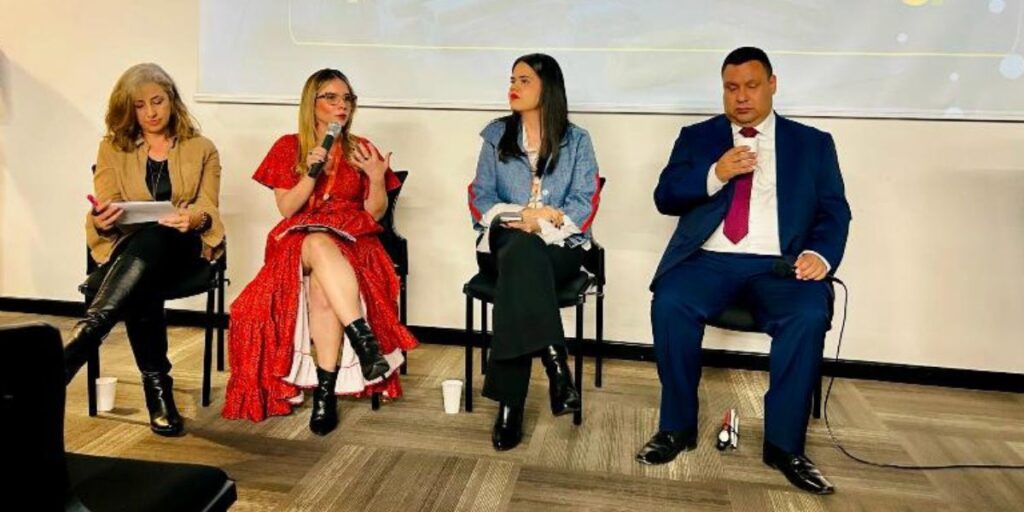 Cuatro panelistas sentados en una mesa durante un conversatorio sobre transporte y personas mayores.