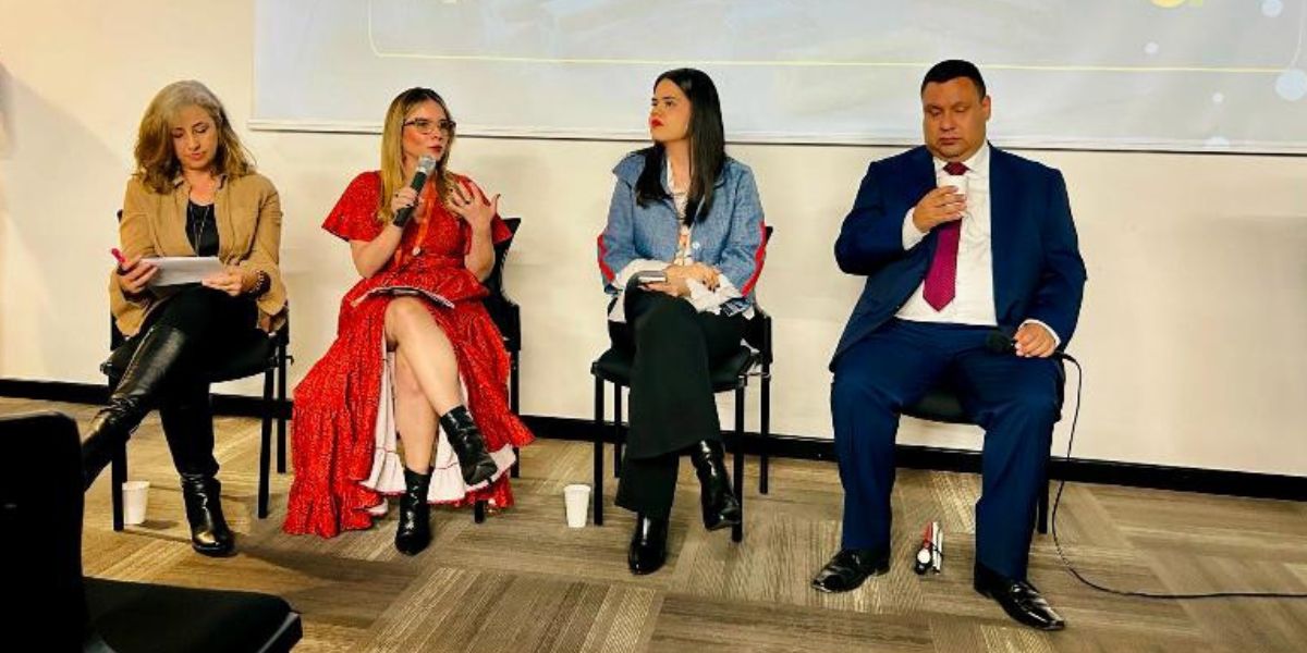 Cuatro panelistas sentados en una mesa durante un conversatorio sobre transporte y personas mayores.