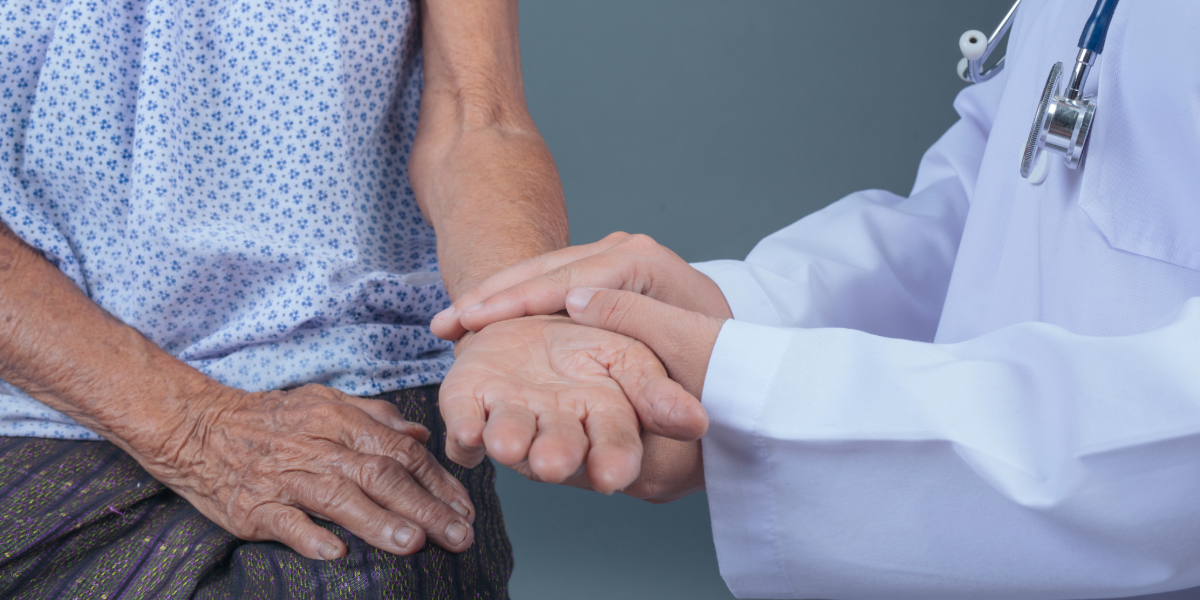 Mano de m&eacute;dico agarrando manos de persona mayor.