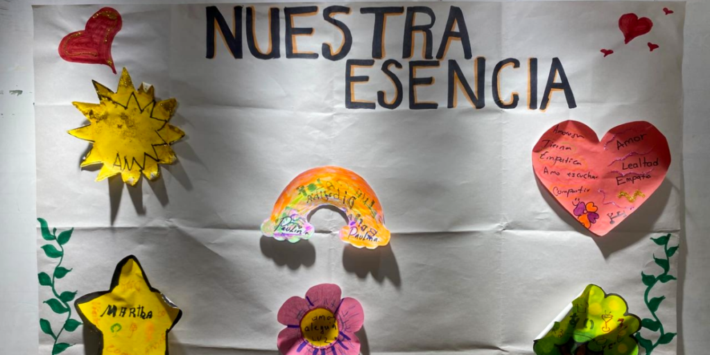 Fotografía de un mapa mental colorido en la oficina de Legatus. Sobre un fondo blanco, el título central dice "Nuestra Esencia" y alrededor se despliegan nubes y ramas con valores como empatía, amor y lealtad ilustrados con colores cálidos y vibrantes. 