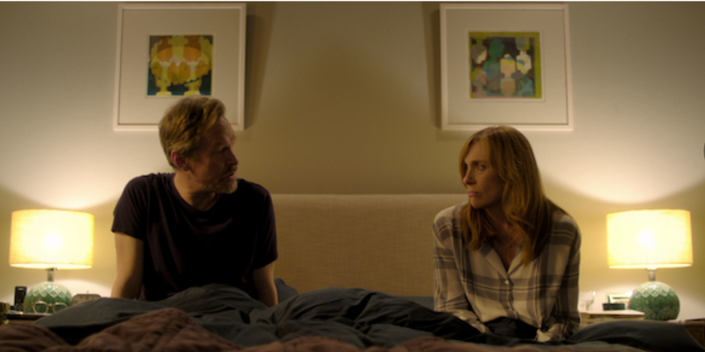 Steven Mackintosh y Toni Collette, protagonistas de la serie 'Wanderlust', en una escena en la habitación se miran seriamente