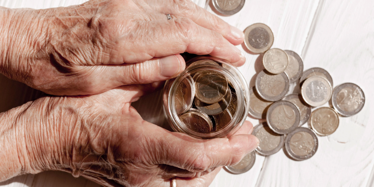 Trabajar después de jubilarse: necesidad o elección Manos con un frasco de monedas.