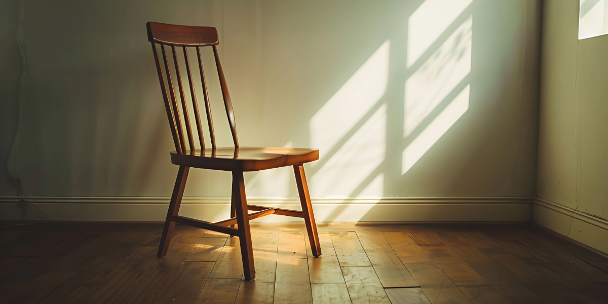 Silla de madera sola en una habitaci&oacute;n vac&iacute;a.